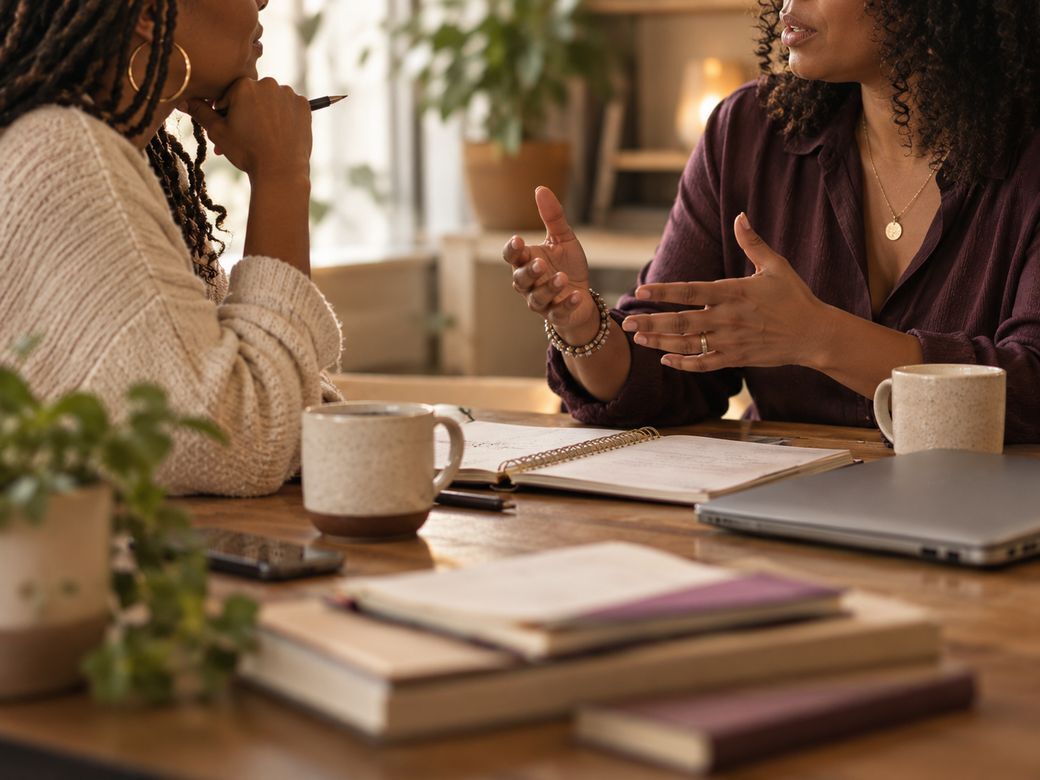 Two women working side by side at a table, a founder and her operations partner aligning on the structure of the business.
